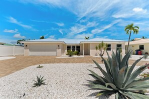 A residential property with a garage, a covered patio, and a landscaped driveway with gravel and cacti. - 💮Private Pool Home-Canal Front-Pet Friendly-3BR The Pink Lily💮 (Fort Myers)