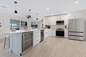 A modern kitchen with white cabinetry, stainless steel appliances, and a central island. - 💮Private Pool Home-Canal Front-Pet Friendly-3BR The Pink Lily💮 (Fort Myers)