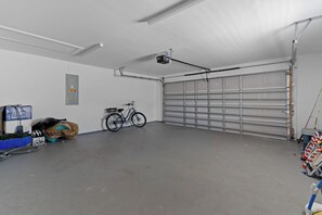 Eine saubere, leere Garage mit einem Fahrrad, einem Elektrowerkzeug und einem blauen Stauraum.