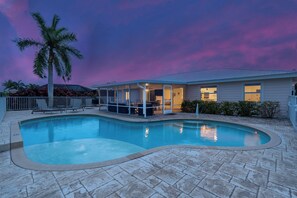 A residential property with a swimming pool, a covered patio, and a house with a visible garage.