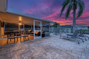 An outdoor patio area with a pool, lounge chairs, and a covered seating area.