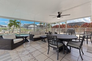 A covered outdoor patio with a pool, seating area, and a view of the surrounding landscape. - 💮Private Pool Home-Canal Front-Pet Friendly-3BR The Pink Lily💮 (Fort Myers)