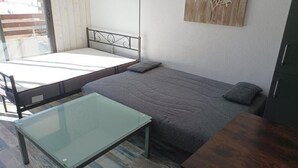 Une petite pièce, de taille modeste, comprenant un lit simple, une table en verre et un meuble en bois.