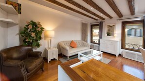 Un salon avec un canapé en cuir marron, un canapé blanc orné d’un coussin orange, une table basse en verre et un meuble blanc.