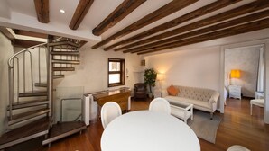 Un salon moderne avec un canapé blanc, une table à manger et un escalier en colimaçon.