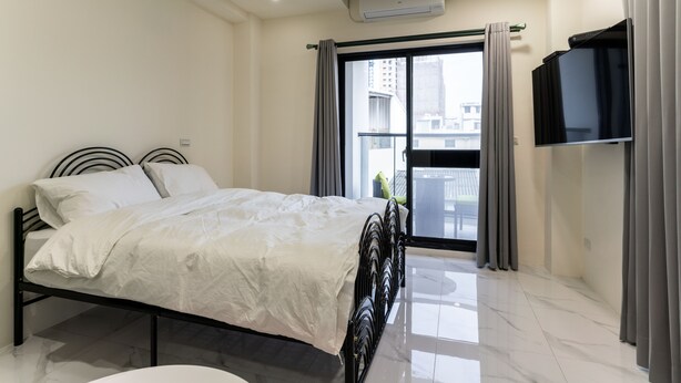A modern bedroom with a bed, a TV, and a balcony with curtains. - Yan Yingchenxi (Kaohsiung)
