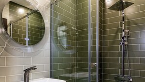 A modern bathroom with a glass-enclosed shower, a round mirror, and a white sink. - Yan Yingchenxi (Kaohsiung)