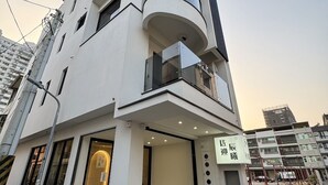 A modern multi-story building with a white facade, large windows, and a ground-level entrance. - Yan Yingchenxi (Kaohsiung)
