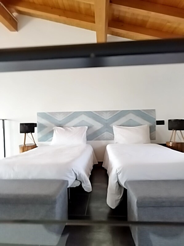 A modern hotel room with two single beds, a geometric patterned headboard, and a wooden ceiling. - Apartamentos Walden by gaiarooms (Morille)