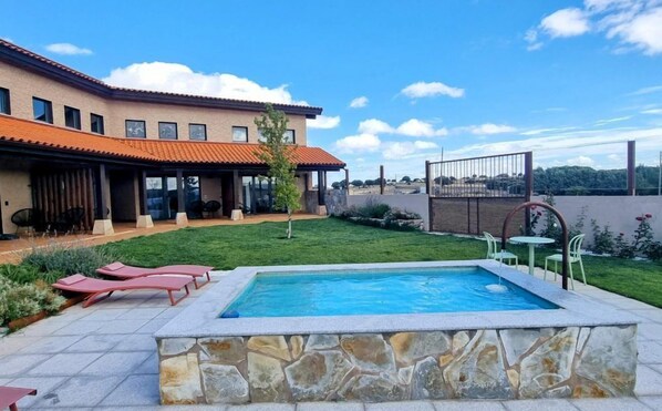 Un patio trasero con piscina, un porche cubierto y vista a una zona residencial.