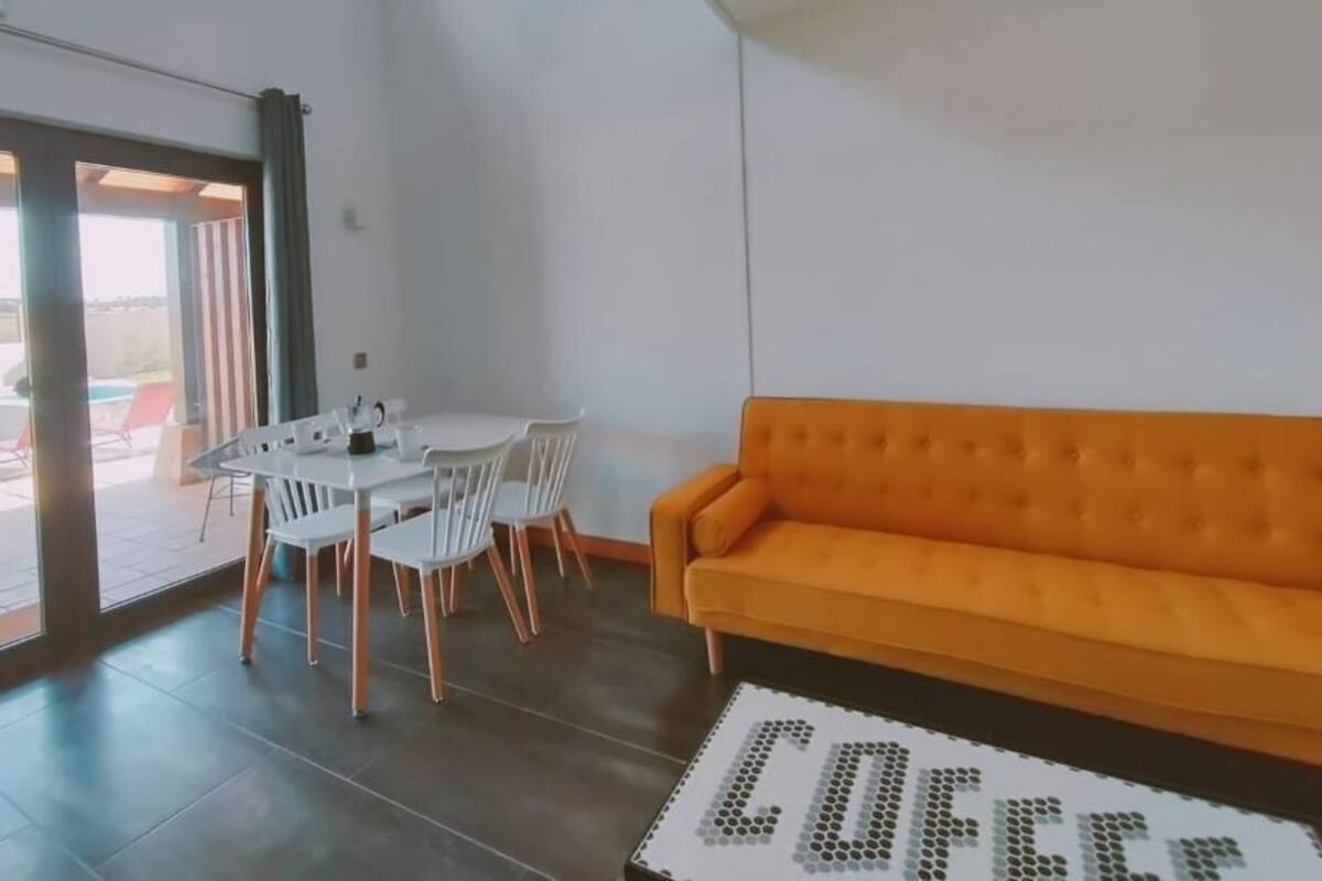 Un salon moderne comprenant un canapé, une table à manger avec des chaises et une table basse ornée d’un motif hexagonal.