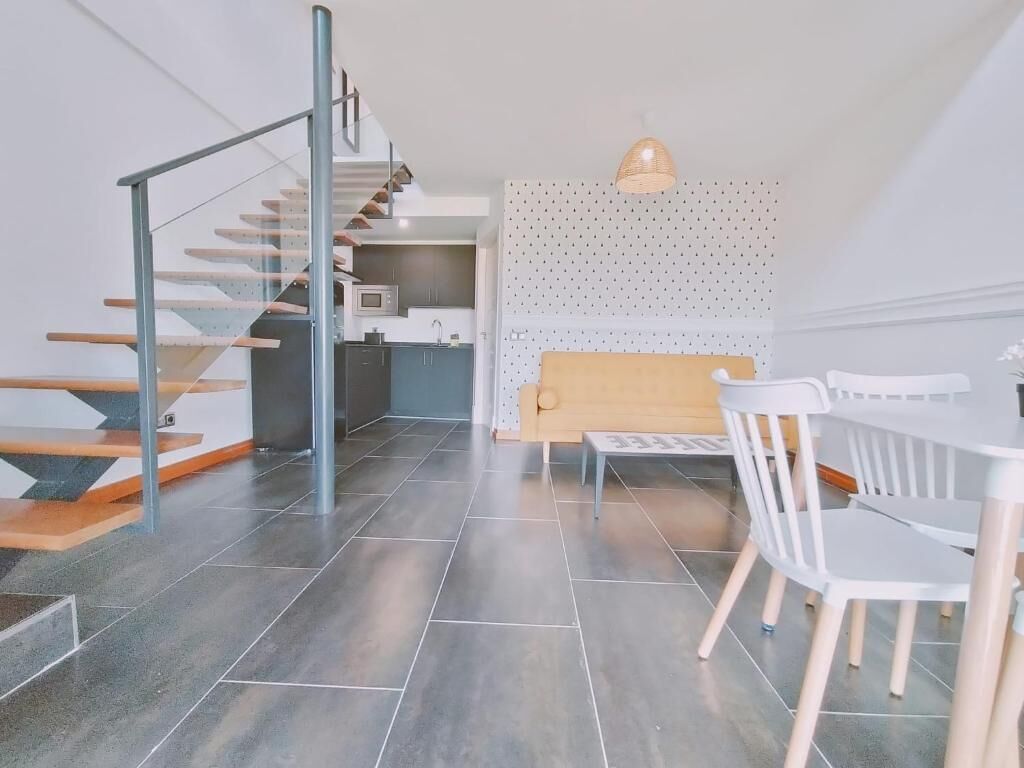 Un interior moderno con una escalera, un comedor y una cocina.