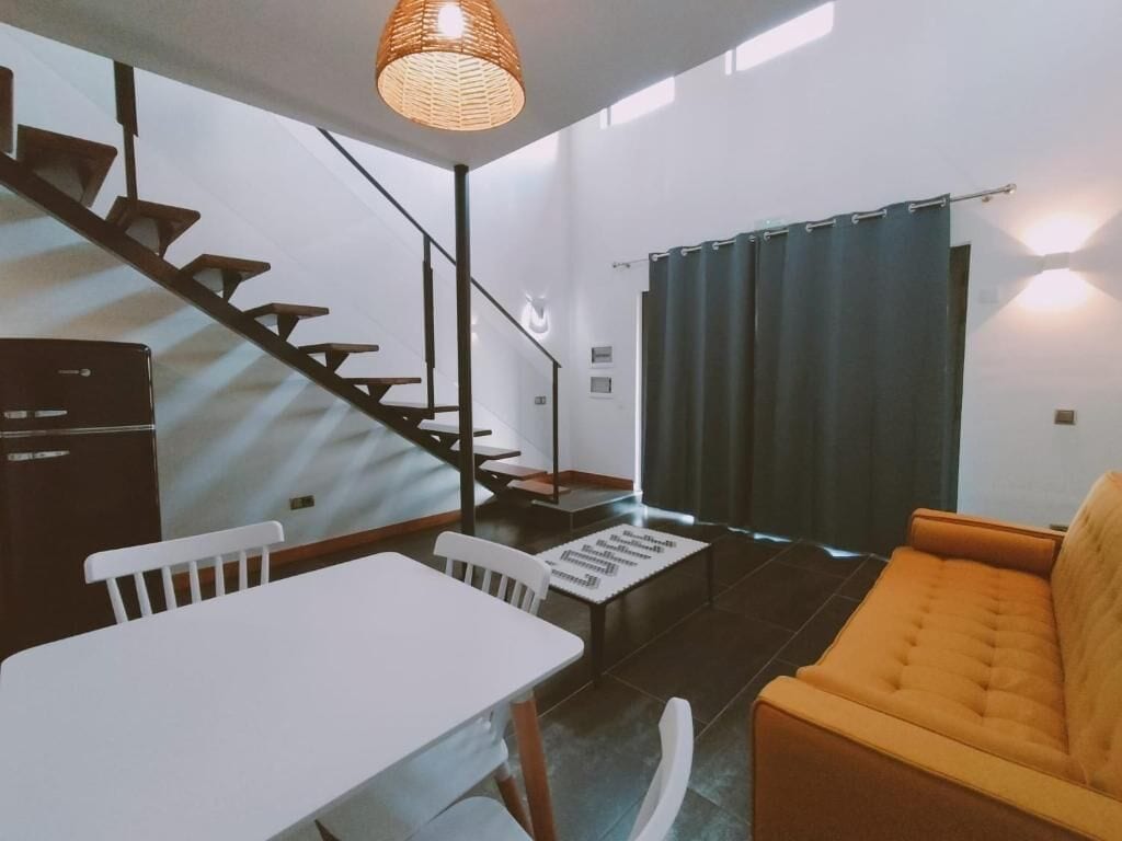 A modern interior with a staircase, a dining area, and a sofa.
