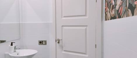 A bathroom with a white sink, mirror, and a door with a floral mural on the wall.
