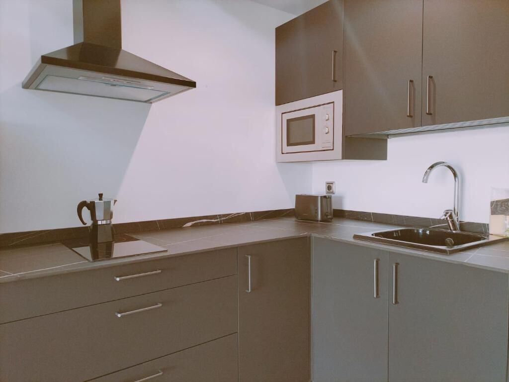A modern kitchen with a microwave, sink, and stainless steel appliances.