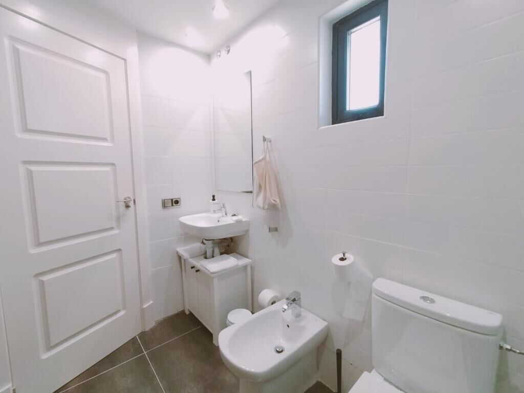 Een badkamer met toilet, bidet, wastafel en een raam.