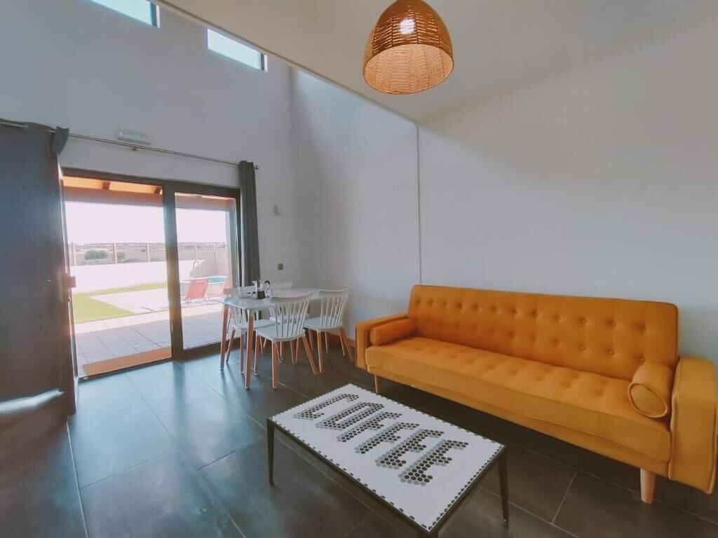 A modern living room with a sofa, a coffee table, and a dining area with chairs.