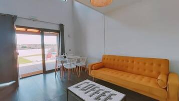 A modern living room with a sofa, a coffee table, and a dining area with chairs.
