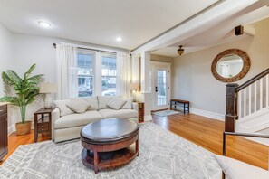 Un salon avec un canapé, une table basse, une lampe, une plante en pot et un escalier.