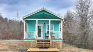 A small, single-story cabin with a porch, wooden deck, and a door. - Vilonia Country Cabin w/ Grill, Fire Pit + More! (Vilonia)