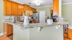 Eine Küche mit Holzausstattung, Granitarbeitsplatten und einer eingebauten Kochinsel mit einer Vase getrockneter Blumen.