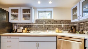 A modern kitchen with white cabinets, a tiled backsplash, and a built-in dishwasher. - Pittsburgh Couple's Retreat ~ 2 Mi to Downtown! (Pittsburgh)