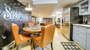 A modern kitchen with a black refrigerator, white cabinets, and a dining area with leather chairs and a round table. - Pittsburgh Couple's Retreat ~ 2 Mi to Downtown! (Pittsburgh)