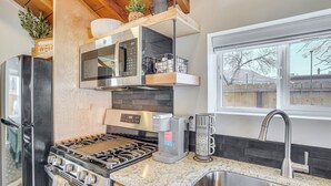 Een moderne keuken met een roestvrijstalen koelkast, een inbouwoven, een gasfornuis, een koffiezetapparaat en een gootsteen met kraan.