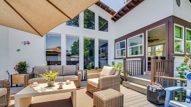 Eine Terrasse im Freien mit Korbmöbeln, einem Tisch und einem Deckenventilator.
