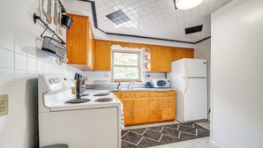 A kitchen with white appliances, wooden cabinets, and a patterned rug. - Spacious Pittsburgh Getaway ~ 2 Mi to Downtown! (Pittsburgh)