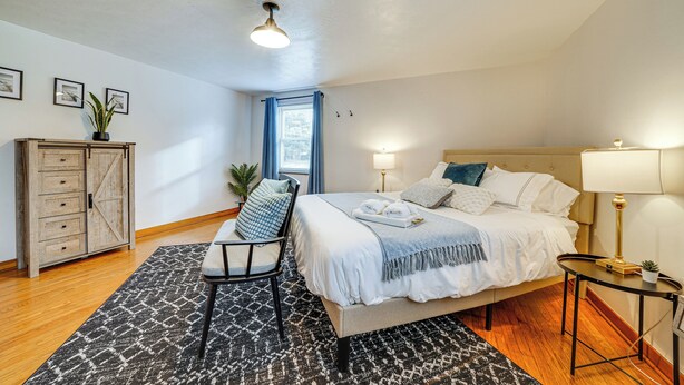 A bedroom with a bed, bedside tables, a chair, a wardrobe, and a window with curtains. - Spacious Pittsburgh Getaway ~ 2 Mi to Downtown! (Pittsburgh)
