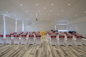 A conference room with rows of white chairs with red sashes, a projector, and a table with a yellow cloth.