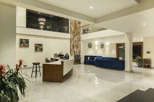 Un área de recepción moderna con un mostrador de madera, asientos azules y obras de arte en las paredes.