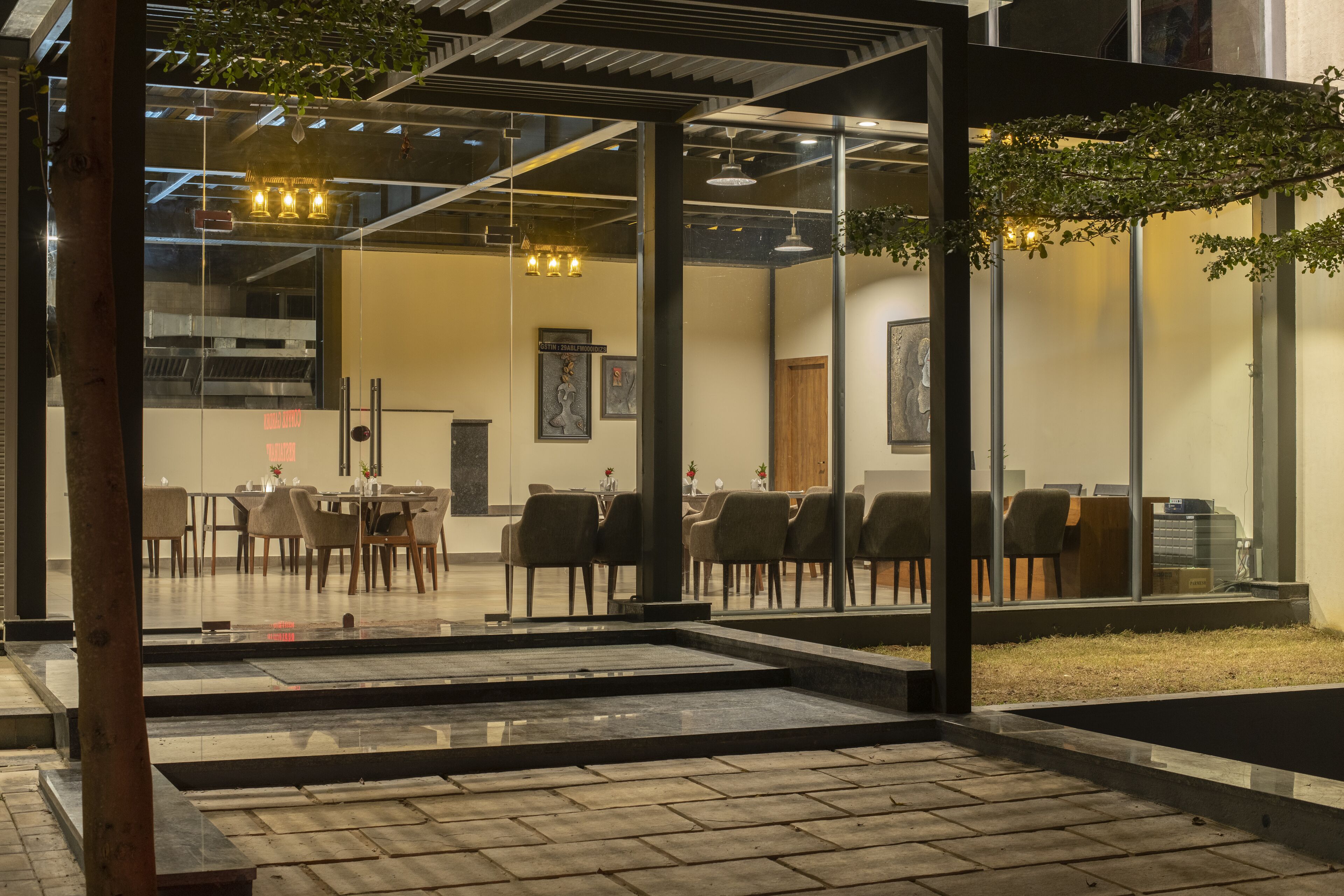 Un comedor interior con mesas y sillas, una partición de vidrio y vistas al exterior.