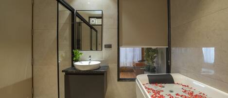 A modern bathroom with a large bathtub, a sink, and a glass shower enclosure.