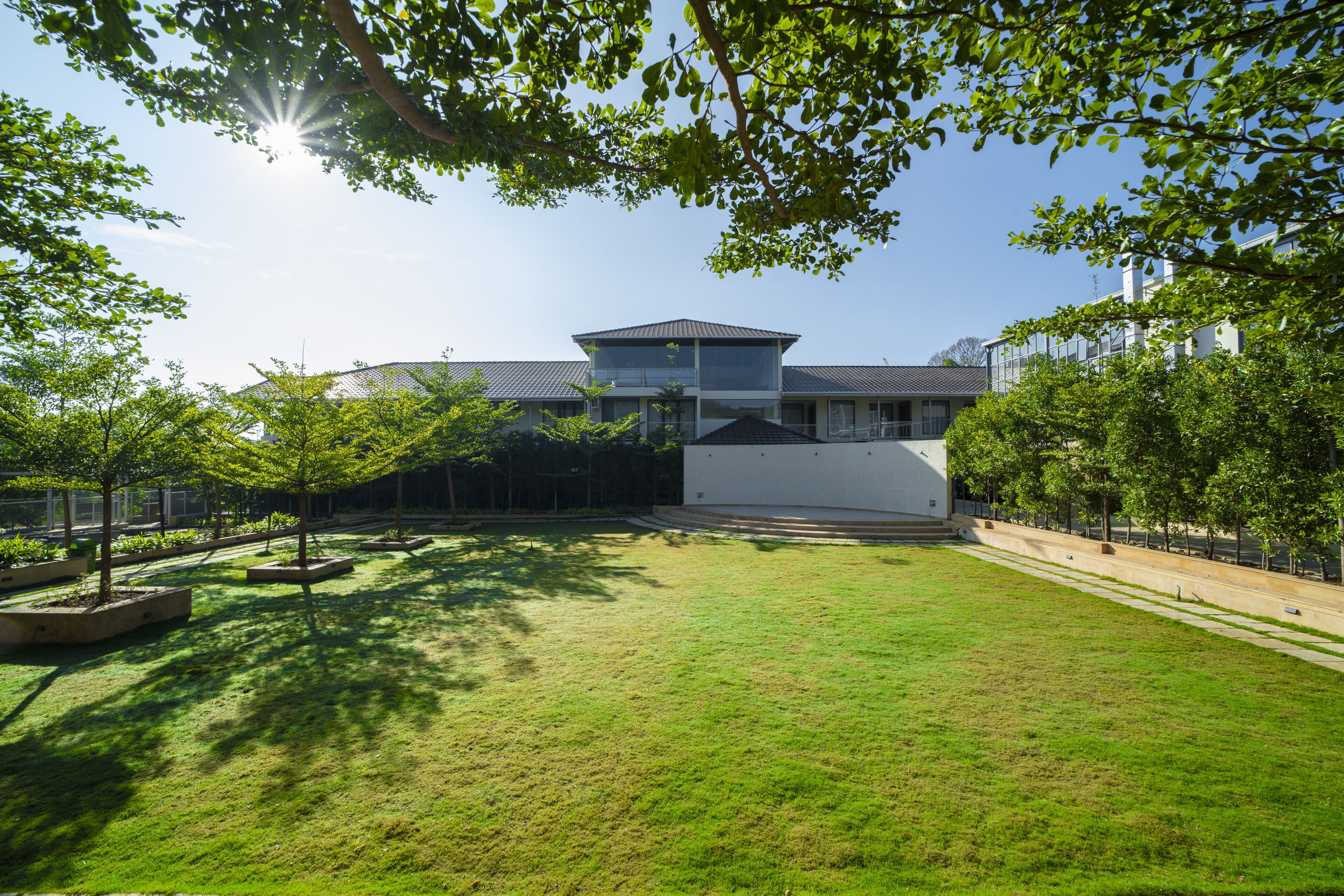 A modern building with a flat roof and large windows, surrounded by a well-maintained lawn and trees.