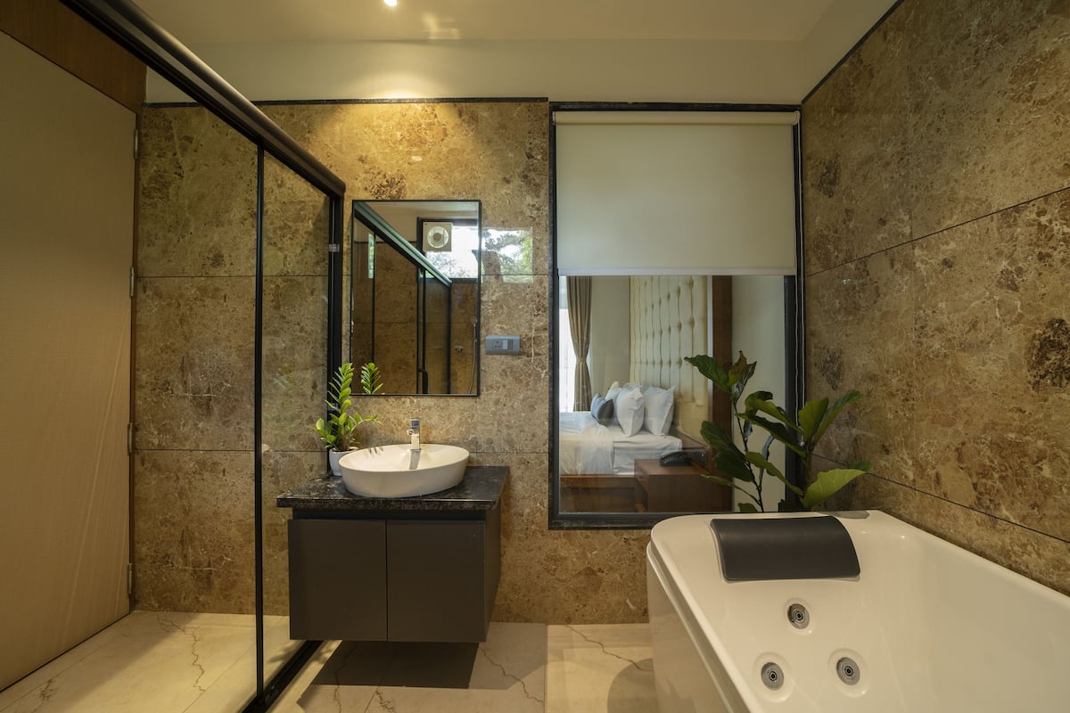 Un baño moderno con un espejo grande, un lavamanos blanco, un mueble de tocador negro y una bañera blanca.