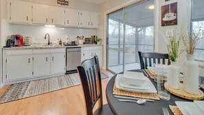 A modern kitchen with white cabinets, a large window, and a dining area set for a meal. - Cozy Lakeview Retreat, Close to Bull Shoals Lake! (Lakeview)