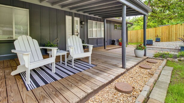 A covered patio with two white Adirondack chairs, a striped rug, and a wooden deck. - Cozy Lakeview Retreat, Close to Bull Shoals Lake! (Lakeview)