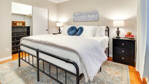 A bedroom with a bed, bedside tables, a dresser, a ceiling fan, and a wall-mounted sign. - Cozy Lakeview Retreat, Close to Bull Shoals Lake! (Lakeview)