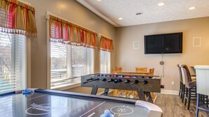 Una stanza con un tavolo da calcio, una TV montata a parete e un'area pranzo con sedie e tavolo.