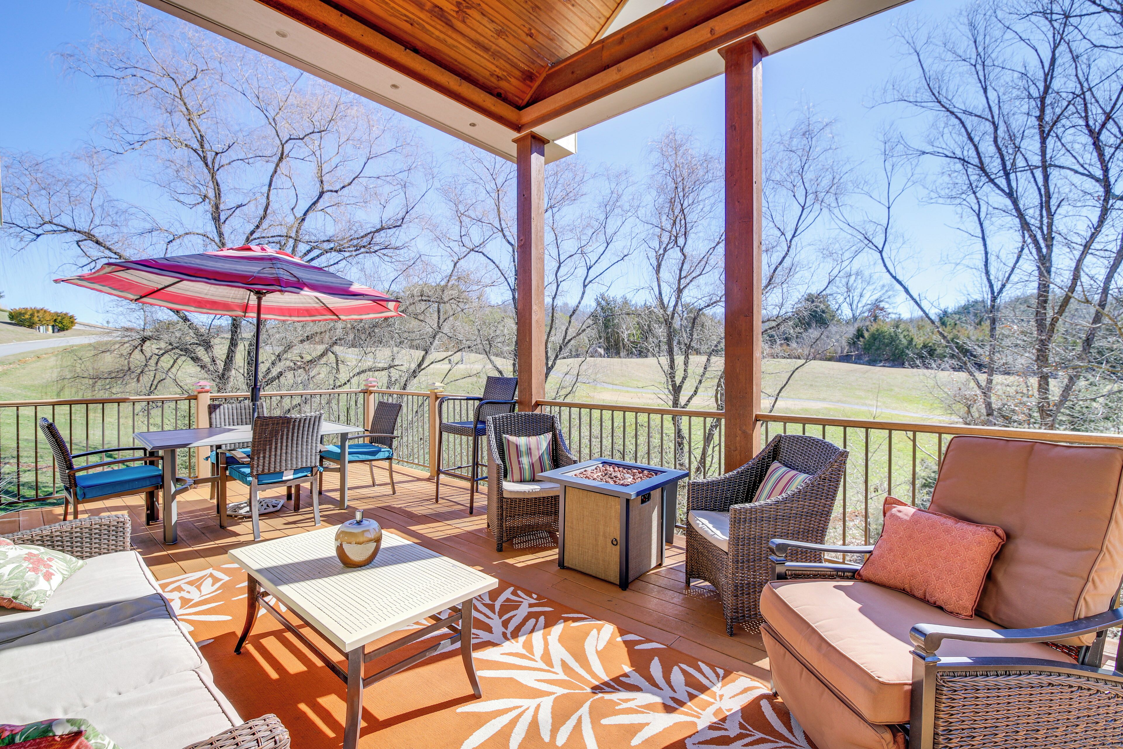 A covered outdoor patio with wicker furniture, a table, and a fire pit.