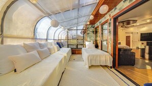 A modern, well-lit room with a curved ceiling, two beds with white bedding, a sofa, and a large window offering a view of the outdoors. - Sauna, Pickleball Court & Game Room: Sultan Villa! (Sultan)