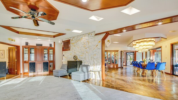 A spacious living area with a large marble floor, wooden ceiling beams, a ceiling fan, and a dining area with blue chairs and a chandelier. - Sauna, Pickleball Court & Game Room: Sultan Villa! (Sultan)