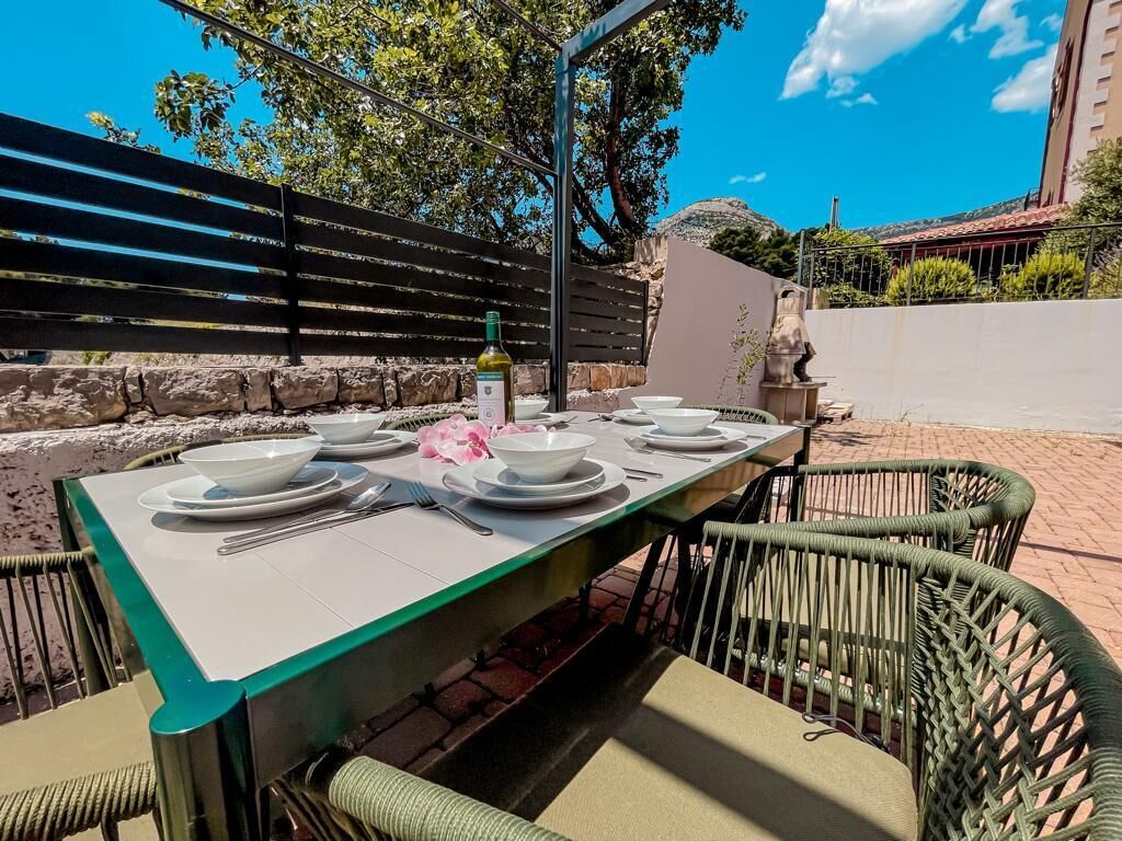 Un área de comedor al aire libre con una mesa dispuesta para cuatro personas, rodeada de sillas de mimbre.