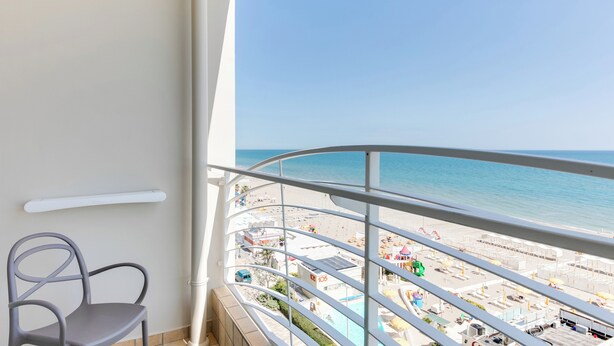 A balcony with a view of a beach and pool area. - Marittimo Riccione (Riccione)