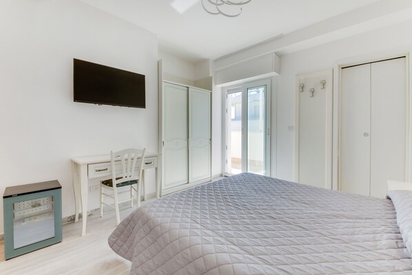 A bedroom with a bed, a desk, a chair, a TV, and a wardrobe. - Marittimo Riccione (Riccione)