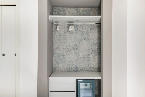A small, enclosed closet with a white door, a white shelf, and a frosted glass door.
