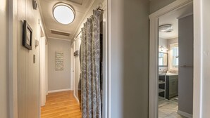 A hallway with a wooden floor, a patterned curtain, and a sign listing names. - House with No Name - Nags Head MP 10.5, Oceanside, 340 Yds to Beach, Pets OK, YR Flex Stays (Nags Head)