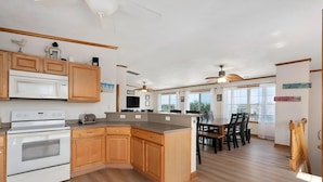 A spacious kitchen with wooden cabinets, a built-in microwave, and a large island. - Skyview by the Sea (Corolla)